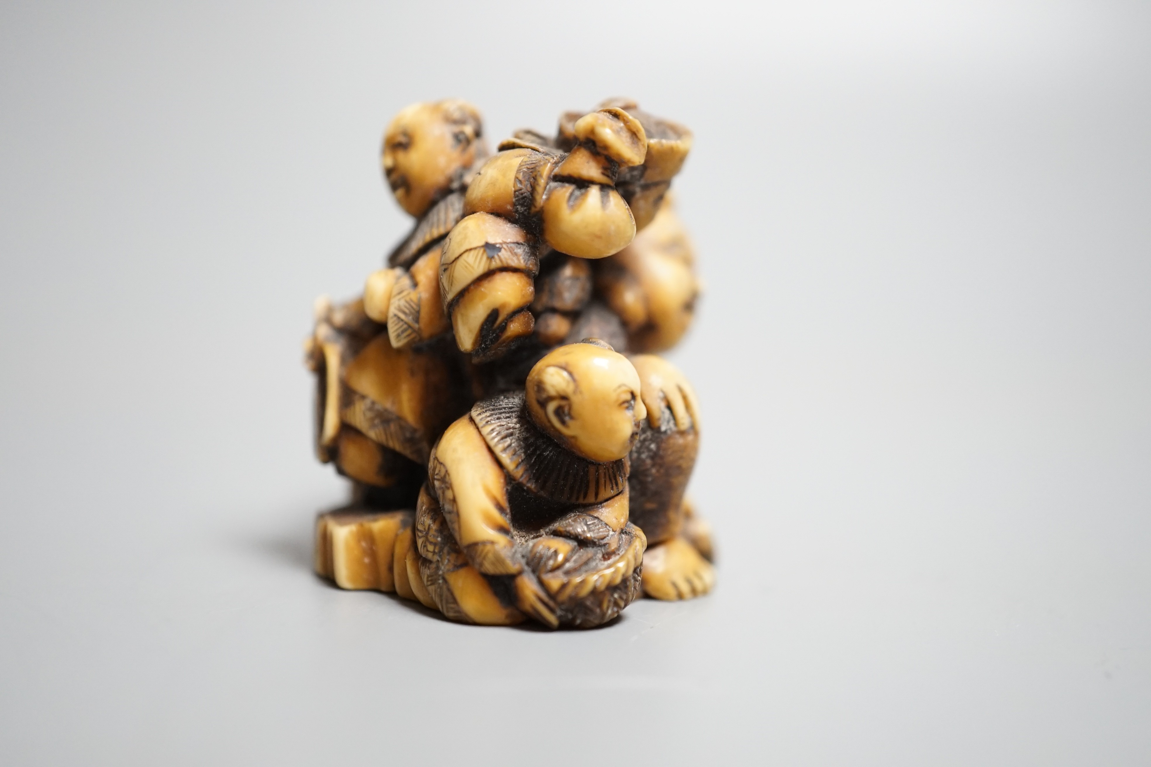 A Japanese ivory netsuke of Hotei with three boys, Meiji period, signed, width 4cm